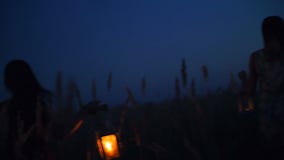 Beautiful girls walking in the field - in the hands holding candle lanterns stock video footage Beautiful girls walking in the field - in the hands holding candle lanterns stock video footage