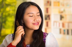 Beautiful hispanic woman wearing white blouse with colorful embroidery, using small hairbrush during makeup routine. Royalty Free Stock Images Beautiful hispanic woman wearing white blouse with colorful embroidery, using small hairbrush during makeup routine. Royalty Free Stock Images