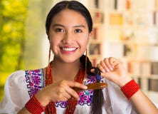 Beautiful hispanic woman wearing white blouse with colorful embroidery, using small hairbrush during makeup routine. Garden background Stock Photography Beautiful hispanic woman wearing white blouse with colorful embroidery, using small hairbrush during makeup routine. Garden background Stock Photography