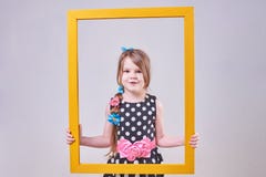 Beautiful little girl, with a funny expression on his face, holding a yellow frame royalty free stock images Beautiful little girl, with a funny expression on his face, holding a yellow frame royalty free stock images