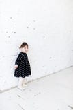 Beautiful little girl in a polka dot dress is standing near the white brick wall and smiling. Birthday celebration, greetings, fun stock images Beautiful little girl in a polka dot dress is standing near the white brick wall and smiling. Birthday celebration, greetings, fun stock images