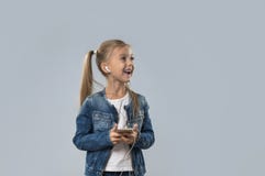 Beautiful Little Girl Using Smart Phone Listen Music Wear Earphones Happy Smiling Look To Copy Space Isolated stock photos Beautiful Little Girl Using Smart Phone Listen Music Wear Earphones Happy Smiling Look To Copy Space Isolated stock photos