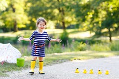 Beautiful little toddler girl playing in park. Adorable child wearing fashion casual clothes and yellow rubber boots. Royalty Free Stock Photo Beautiful little toddler girl playing in park. Adorable child wearing fashion casual clothes and yellow rubber boots. Royalty Free Stock Photo