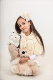 Beautiful long-haired girl dressed in a white coat. The child is holding soft toys on isolated grey background. stock photos Beautiful long-haired girl dressed in a white coat. The child is holding soft toys on isolated grey background. stock photos