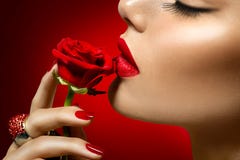 Beautiful model woman kissing red rose flower