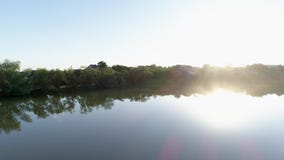Beautiful nature at sunrise, clean lake among green trees at bright sunlight