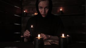 Beautiful nun holds a candle and reading old book of highlights the flame. Christianity concept