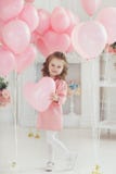 Beautiful preschool girl in a white studio with pink heart-shaped balloons stock photo Beautiful preschool girl in a white studio with pink heart-shaped balloons stock photo