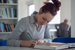 Beautiful redhead girl working and writing notes on the desk wit royalty free stock images Beautiful redhead girl working and writing notes on the desk wit royalty free stock images