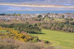 Beautiful scenic aerial-like bright view of golf course with trees and yellow gorse, Irish sea, beach, Dublin bay, house roofs