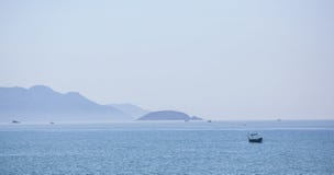 A beautiful seascape, a sailboat floating in the distance amidst majestic mountains. Royalty Free Stock Images A beautiful seascape, a sailboat floating in the distance amidst majestic mountains. Royalty Free Stock Images