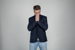 A beautiful sexy bearded man with a beautiful hairdo closes her face with her hands. a man is disappointed. dressed in a jacket, royalty free stock images A beautiful sexy bearded man with a beautiful hairdo closes her face with her hands. a man is disappointed. dressed in a jacket, royalty free stock images