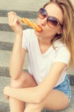 Beautiful sexy girl sitting on the stairs in the town in sunglasses and denim shorts sexy licking colorful ice lolly Royalty Free Stock Photo Beautiful sexy girl sitting on the stairs in the town in sunglasses and denim shorts sexy licking colorful ice lolly Royalty Free Stock Photo