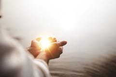 Beautiful shot of Jesus Christ holding hope and light in his palms with a blurred background