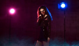 Beautiful singing girl curly afro hair. Beauty woman singer sing with microphone karaoke song on stage smoke, spotlights stock photos Beautiful singing girl curly afro hair. Beauty woman singer sing with microphone karaoke song on stage smoke, spotlights stock photos