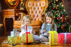 Beautiful sisters sit on the floor near the Christmas tree stock photos Beautiful sisters sit on the floor near the Christmas tree stock photos