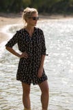 Blonde woman stand in water at the beach in short dress, and sunglasses. Backlight. stock image Blonde woman stand in water at the beach in short dress, and sunglasses. Backlight. stock image