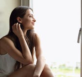 Beautiful smiling positive woman sitting near the window and loo Royalty Free Stock Images Beautiful smiling positive woman sitting near the window and loo Royalty Free Stock Images