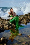 Teenage girl in a mermaid costume is sitting with her eyes closed on a rock on the beach against the backdrop of raging waves. royalty free stock photo Teenage girl in a mermaid costume is sitting with her eyes closed on a rock on the beach against the backdrop of raging waves. royalty free stock photo