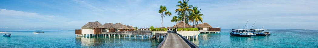 Beautiful Tropical Beach Panorama Of Bungalos With Bridge Near The Ocean With Palms Trees And Boats At Maldives Royalty Free Stock Photography Beautiful Tropical Beach Panorama Of Bungalos With Bridge Near The Ocean With Palms Trees And Boats At Maldives Royalty Free Stock Photography
