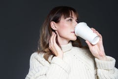 Beautiful woman with long hair wearing sweater holds paper disposable coffee cup. Drinking coffee with relaxed profile face. royalty free stock images Beautiful woman with long hair wearing sweater holds paper disposable coffee cup. Drinking coffee with relaxed profile face. royalty free stock images