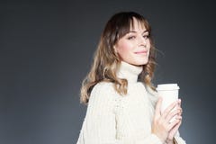 Beautiful woman with long hair wearing sweater holds holds paper disposable coffee cup. Smiling. Space for design template layout. stock photography Beautiful woman with long hair wearing sweater holds holds paper disposable coffee cup. Smiling. Space for design template layout. stock photography