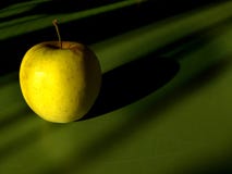 Beautiful yellow apple closeup in the sun light with shadow on a green table background - artistic fruit concept royalty free stock images Beautiful yellow apple closeup in the sun light with shadow on a green table background - artistic fruit concept royalty free stock images