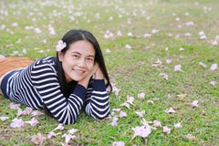 Beautiful young Asian woman lying on green field with fully fall pink flower in the garden outdoor royalty free stock photo Beautiful young Asian woman lying on green field with fully fall pink flower in the garden outdoor royalty free stock photo