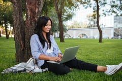 Beautiful young asian woman sitting under a tree and chatting on Stock Image Beautiful young asian woman sitting under a tree and chatting on Stock Image