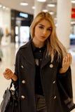 Beautiful young blond woman with a pretty face in a fashionable stylish coat with a leather black fashion handbag royalty free stock photography Beautiful young blond woman with a pretty face in a fashionable stylish coat with a leather black fashion handbag royalty free stock photography