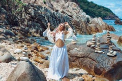 Beautiful young boho style woman in white dress on stone beach Royalty Free Stock Photography Beautiful young boho style woman in white dress on stone beach Royalty Free Stock Photography