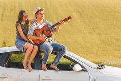 Beautiful young couple enjoying on car roof against yellow field background. royalty free stock photos Beautiful young couple enjoying on car roof against yellow field background. royalty free stock photos