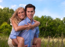 Beautiful, Young Couple Piggybacking In Tall Grass Stock Photo