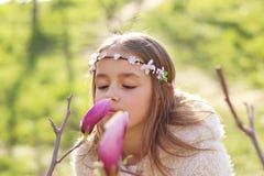 Beautiful young girl with handmade hair wreath on her head looking at magnolia flower and smelling it aroma stock image Beautiful young girl with handmade hair wreath on her head looking at magnolia flower and smelling it aroma stock image