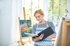 Pretty blode girl looking on a album and smiling. Art concept, stock images Pretty blode girl looking on a album and smiling. Art concept, stock images
