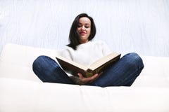 Beautiful young girl reading book lying on the couch. royalty free stock photography Beautiful young girl reading book lying on the couch. royalty free stock photography