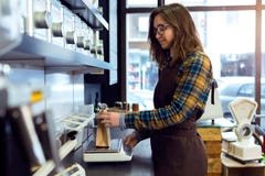 Beautiful young saleswoman weighing coffee beans in a retail store selling coffee. royalty free stock photos Beautiful young saleswoman weighing coffee beans in a retail store selling coffee. royalty free stock photos