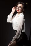 Beautiful young business woman with dark updo hair looking direct over her trendy glasses in modern frame. royalty free stock photo Beautiful young business woman with dark updo hair looking direct over her trendy glasses in modern frame. royalty free stock photo