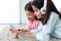Beautiful young sisters listening to music with digital tablet a Royalty Free Stock Image Beautiful young sisters listening to music with digital tablet a Royalty Free Stock Image
