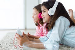Beautiful young sisters listening to music with digital tablet a Royalty Free Stock Image Beautiful young sisters listening to music with digital tablet a Royalty Free Stock Image