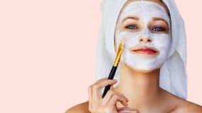 Beautiful young woman applying facial mask on her face with brush. Skin care and treatment, spa, natural beauty and cosmetology royalty free stock photography Beautiful young woman applying facial mask on her face with brush. Skin care and treatment, spa, natural beauty and cosmetology royalty free stock photography