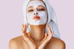 Beautiful young woman applying facial mask on her face. Skin care and treatment, spa, natural beauty and cosmetology concept stock photo Beautiful young woman applying facial mask on her face. Skin care and treatment, spa, natural beauty and cosmetology concept stock photo