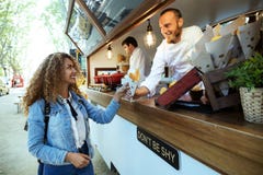 Beautiful young woman buying barbecue potatoes on a food truck. Stock Images Beautiful young woman buying barbecue potatoes on a food truck. Stock Images