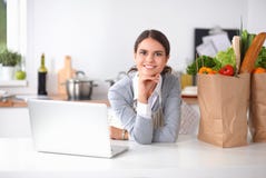 Beautiful young woman cooking looking at laptop screen with receipt in the kitchen royalty free stock photos Beautiful young woman cooking looking at laptop screen with receipt in the kitchen royalty free stock photos