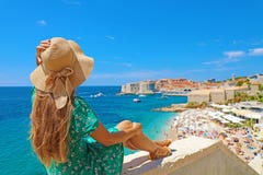Beautiful young woman with hat sitting on wall looking at stunning panoramic village of Dubrovnik in Croatia, Europe royalty free stock photos Beautiful young woman with hat sitting on wall looking at stunning panoramic village of Dubrovnik in Croatia, Europe royalty free stock photos