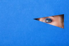 Beautiful young woman in a hole in blue paper, beautiful bright make-up royalty free stock image Beautiful young woman in a hole in blue paper, beautiful bright make-up royalty free stock image