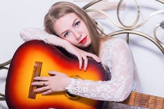 Beautiful young woman playing music on a bed with happiness and guitar stock image Beautiful young woman playing music on a bed with happiness and guitar stock image