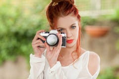 Beautiful young woman with red hair sitting in the garden taking pictures with camera royalty free stock photo Beautiful young woman with red hair sitting in the garden taking pictures with camera royalty free stock photo