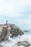 Beautiful young woman sitting on the stone on the seashore. Tropical island of Bali, Indonesia. royalty free stock images Beautiful young woman sitting on the stone on the seashore. Tropical island of Bali, Indonesia. royalty free stock images
