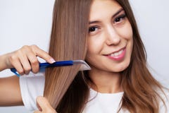 Beautiful young woman takes care of her hair, combing long hair with a comb